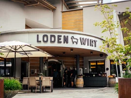 Der Lodenwirt in Vintl | Hotel, Residence & Restaurant Außenansicht des Restaurants Lodenwirt mit Sitzbereich und Sonnenschirm