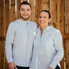Inviate una richiesta al Lodenwirt a Vandoies Uomo e donna sorridenti con camicie bianche davanti a parete di legno