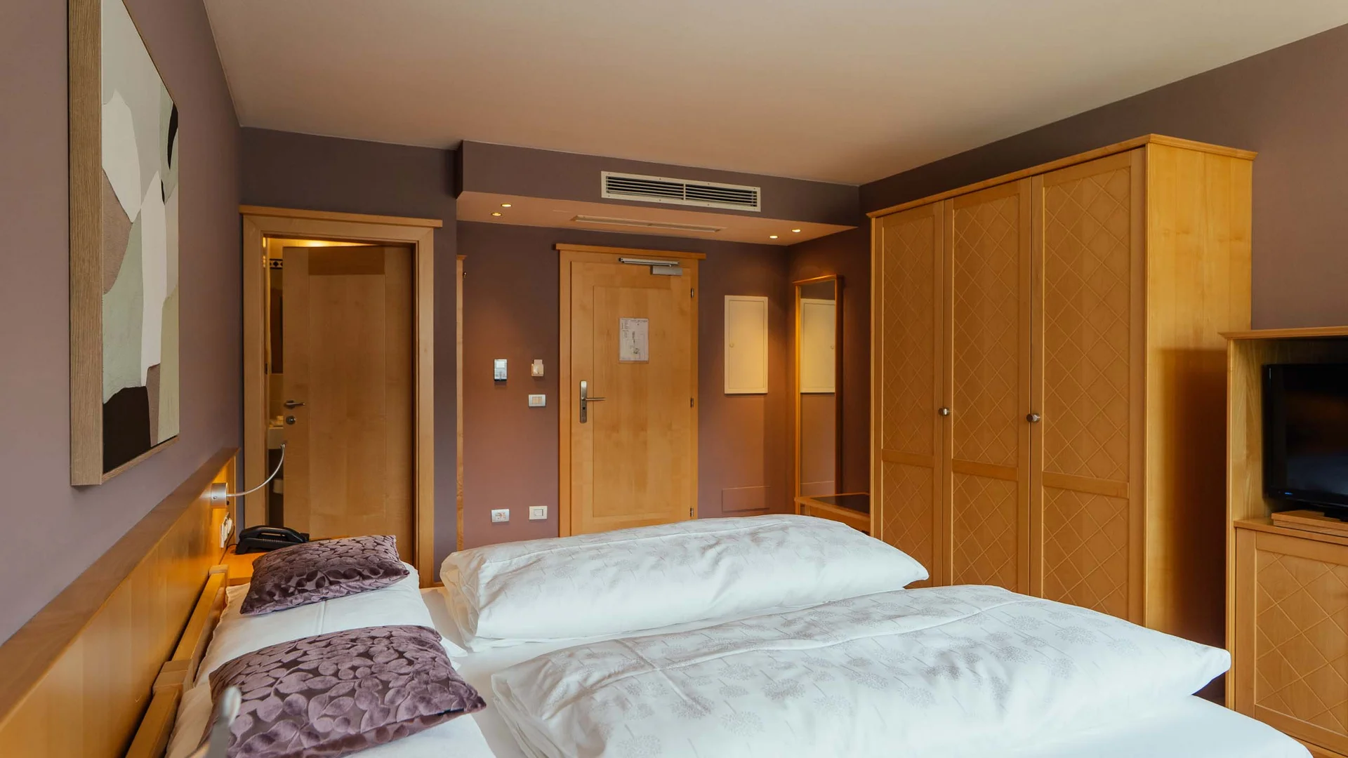 Camera d'hotel accogliente con letto matrimoniale, armadio e televisore