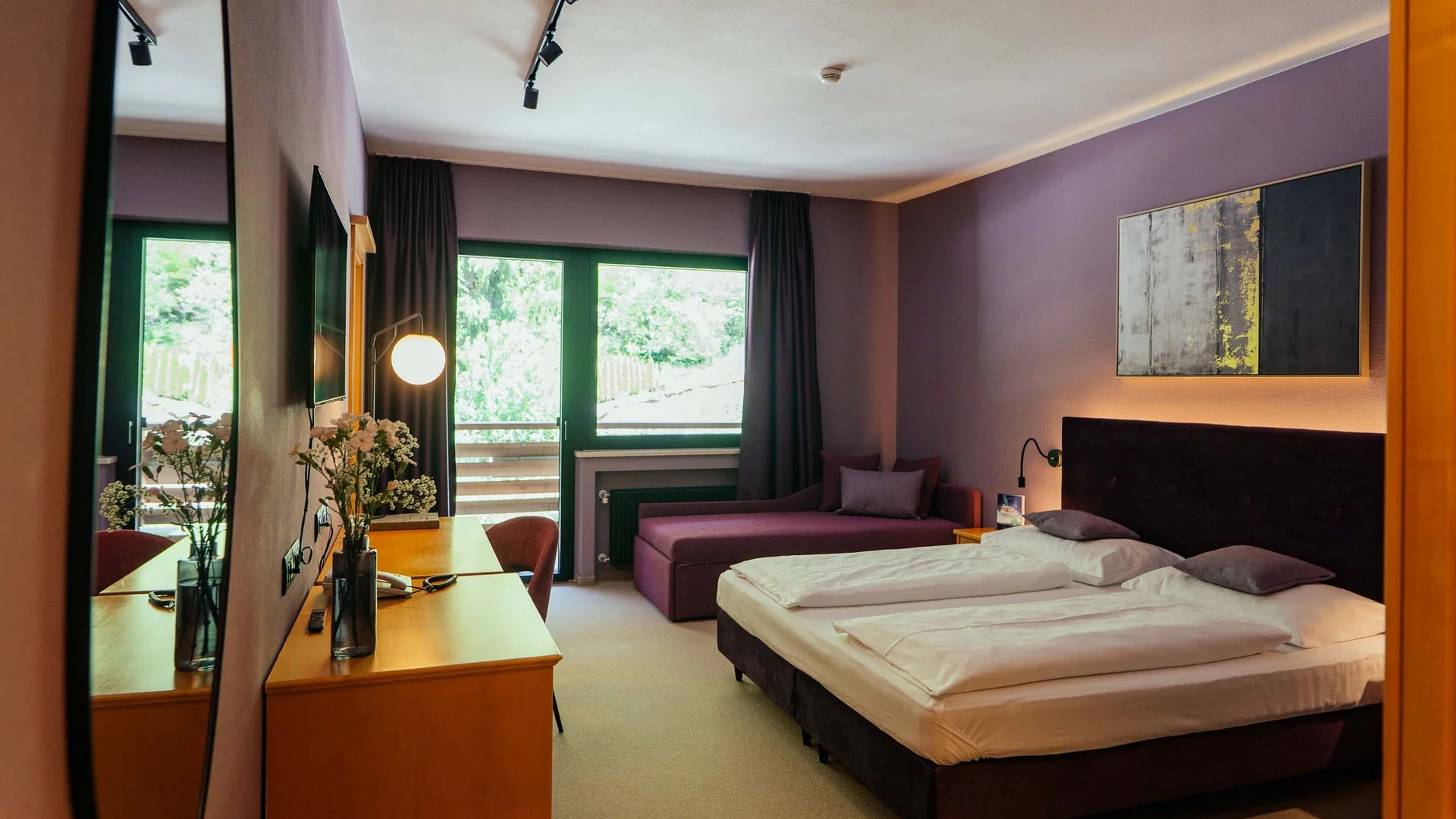 Modernes Hotelzimmer mit Doppelbett, Schreibtisch und großem Fenster