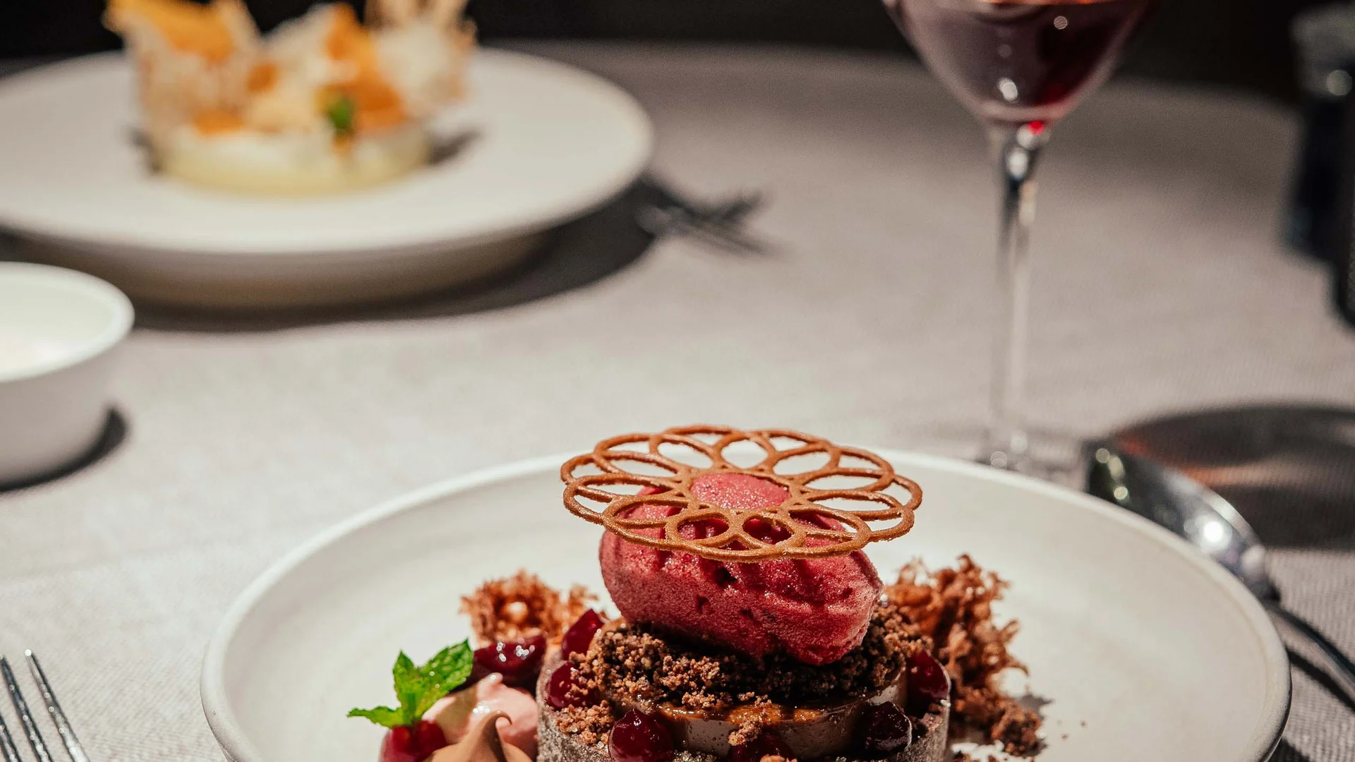 Dessert raffinato con sorbetto rosso e decorazioni su piatto bianco in ristorante