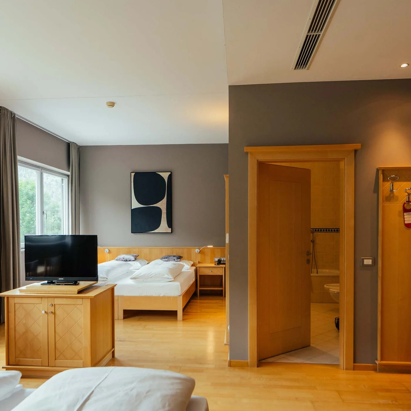 Il Lodenwirt a Vandoies | Hotel, residence e ristorante Camera d'hotel luminosa con letto matrimoniale, TV, tavolo da pranzo e bagno aperto