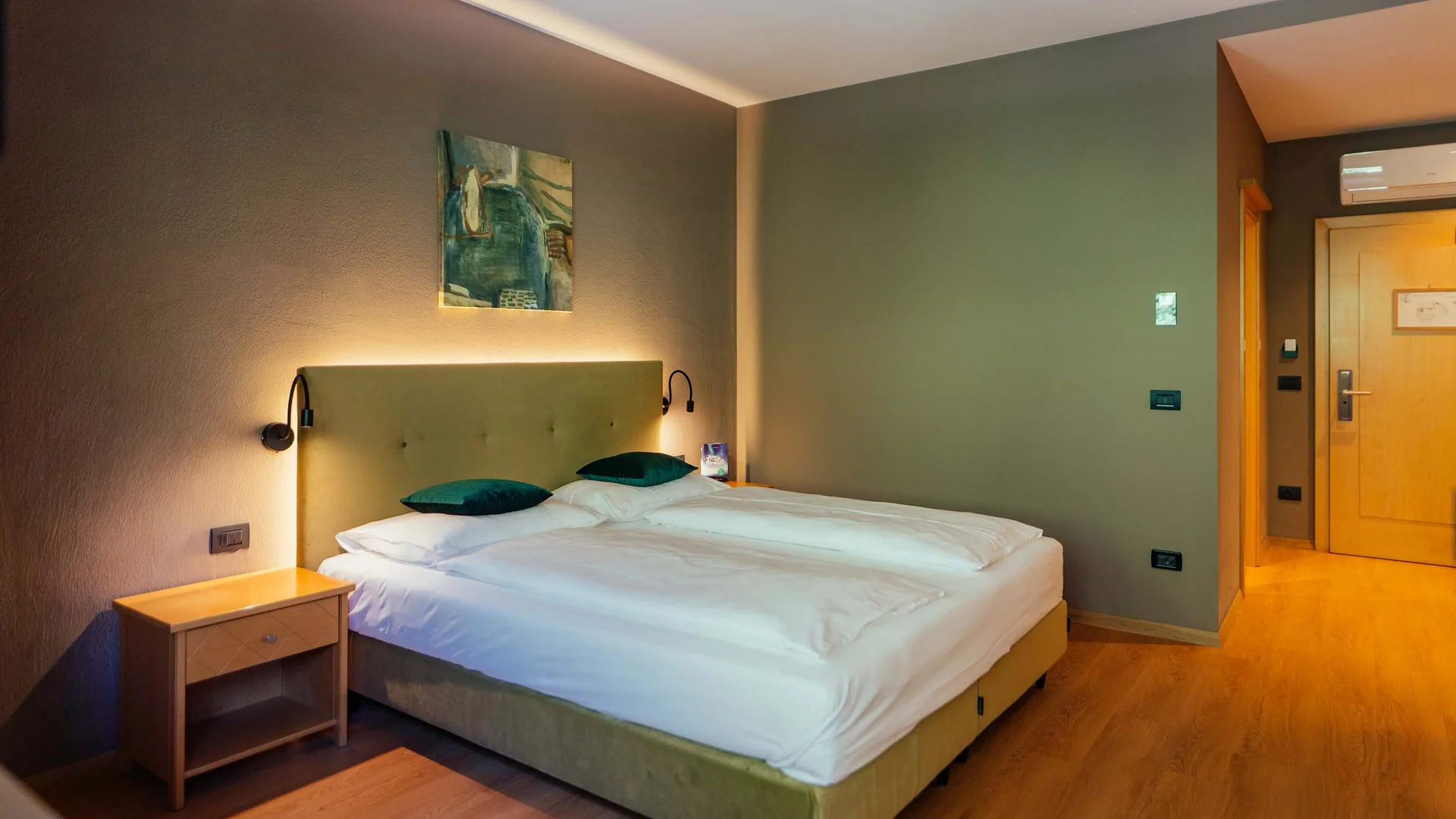 Modernes Hotelzimmer mit Doppelbett, Nachttisch und indirekter Beleuchtung