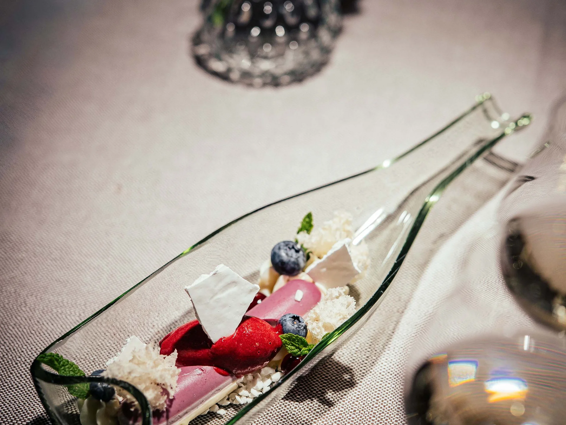 Der Lodenwirt in Vintl | Hotel, Residence & Restaurant Feines Dessert mit Beeren und Minze in einer Glasflasche auf Tisch