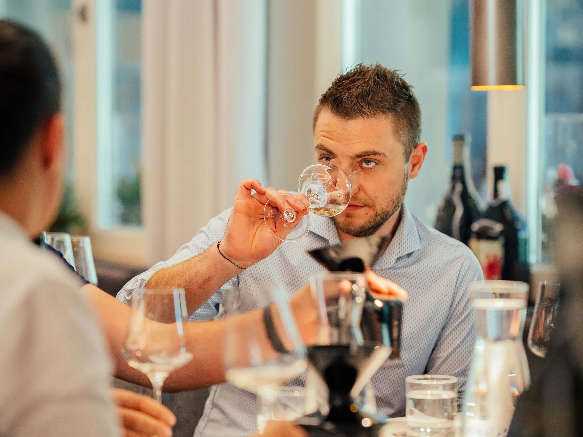 Uomo annusa un calice di vino durante una degustazione in ambiente elegante