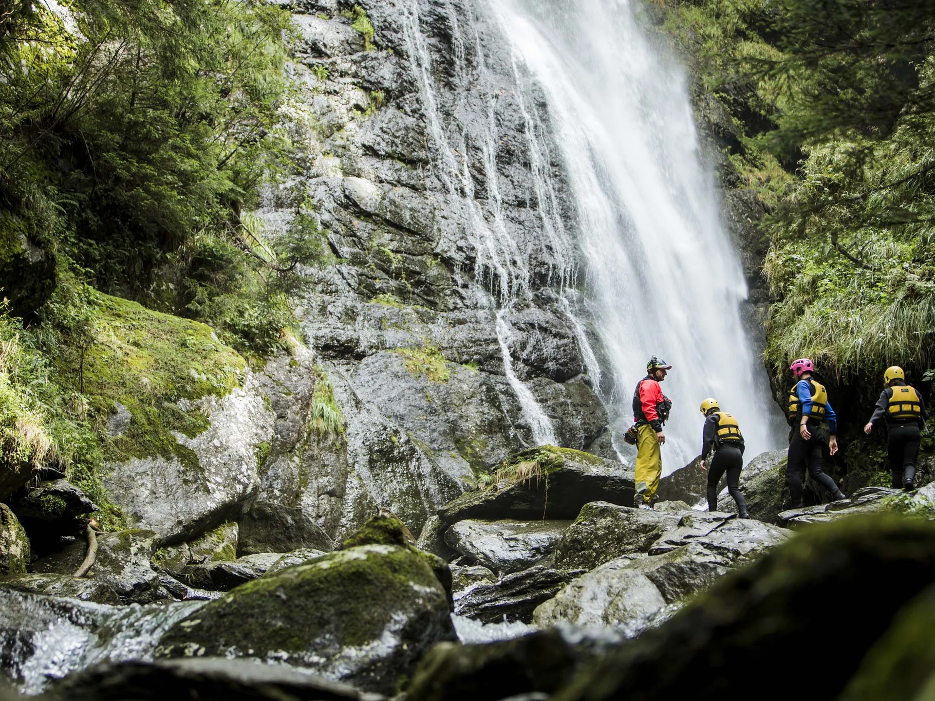 Le vostre vacanze in Val Pusteria Quattro persone davanti a una cascata in una zona rocciosa e boscosa