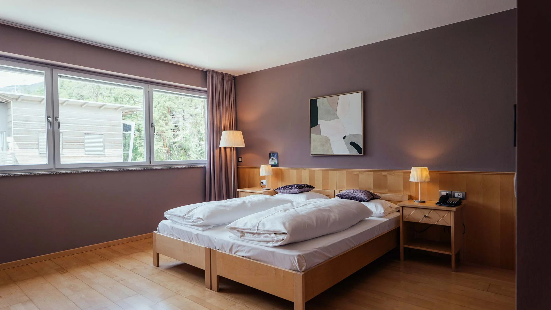 Camera d'hotel moderna con letto matrimoniale, comodini e grande finestra con vista esterna