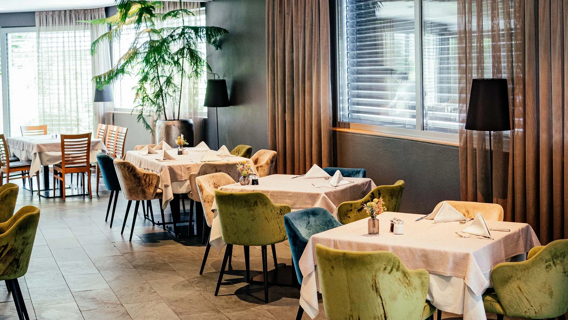 Freut euch auf dieses Hotel in Vintl. Modernes Restaurant mit gedeckten Tischen und bunten Stühlen