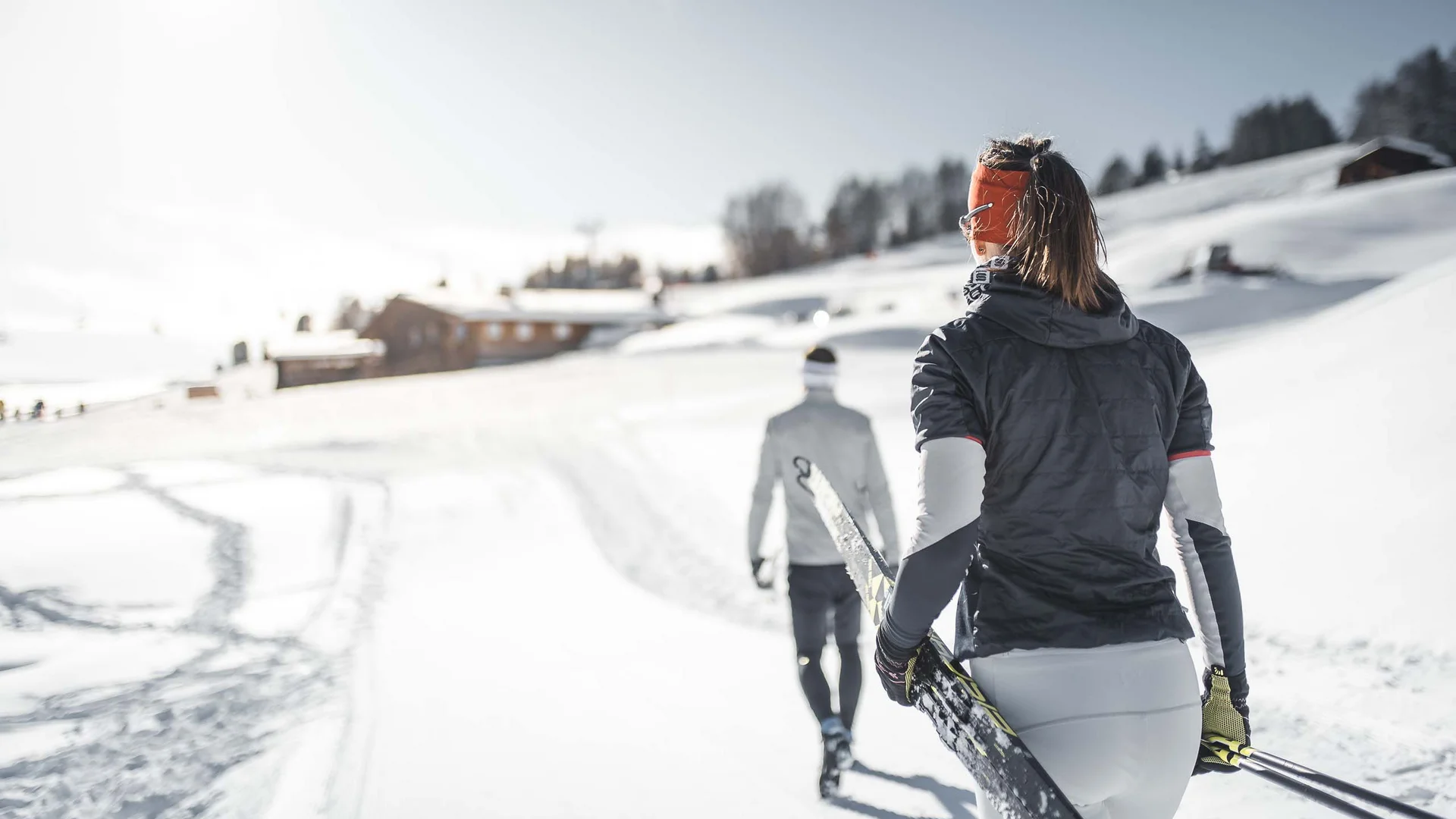 Hotel & Residence Lodenwirt photo gallery Two skiers carry their skis through a snowy mountain landscape