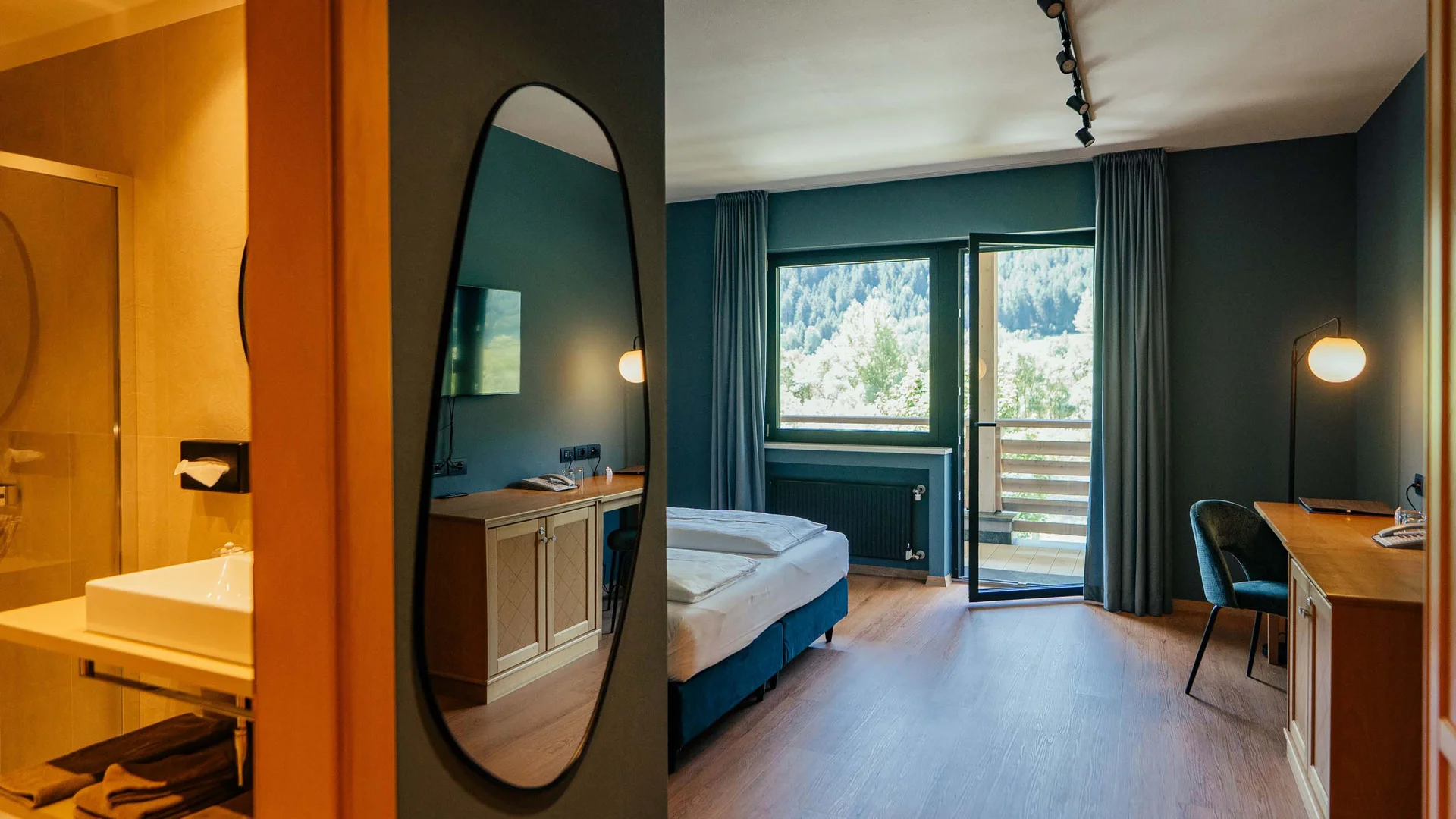 Modernes Hotelzimmer mit Doppelbett, Schreibtisch und Balkon mit Bergblick