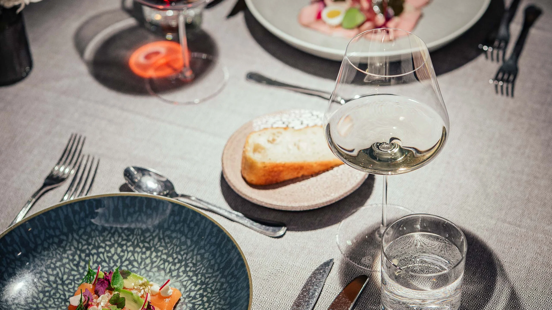 Tavola apparecchiata con due portate, vino rosso e bianco, acqua e pane