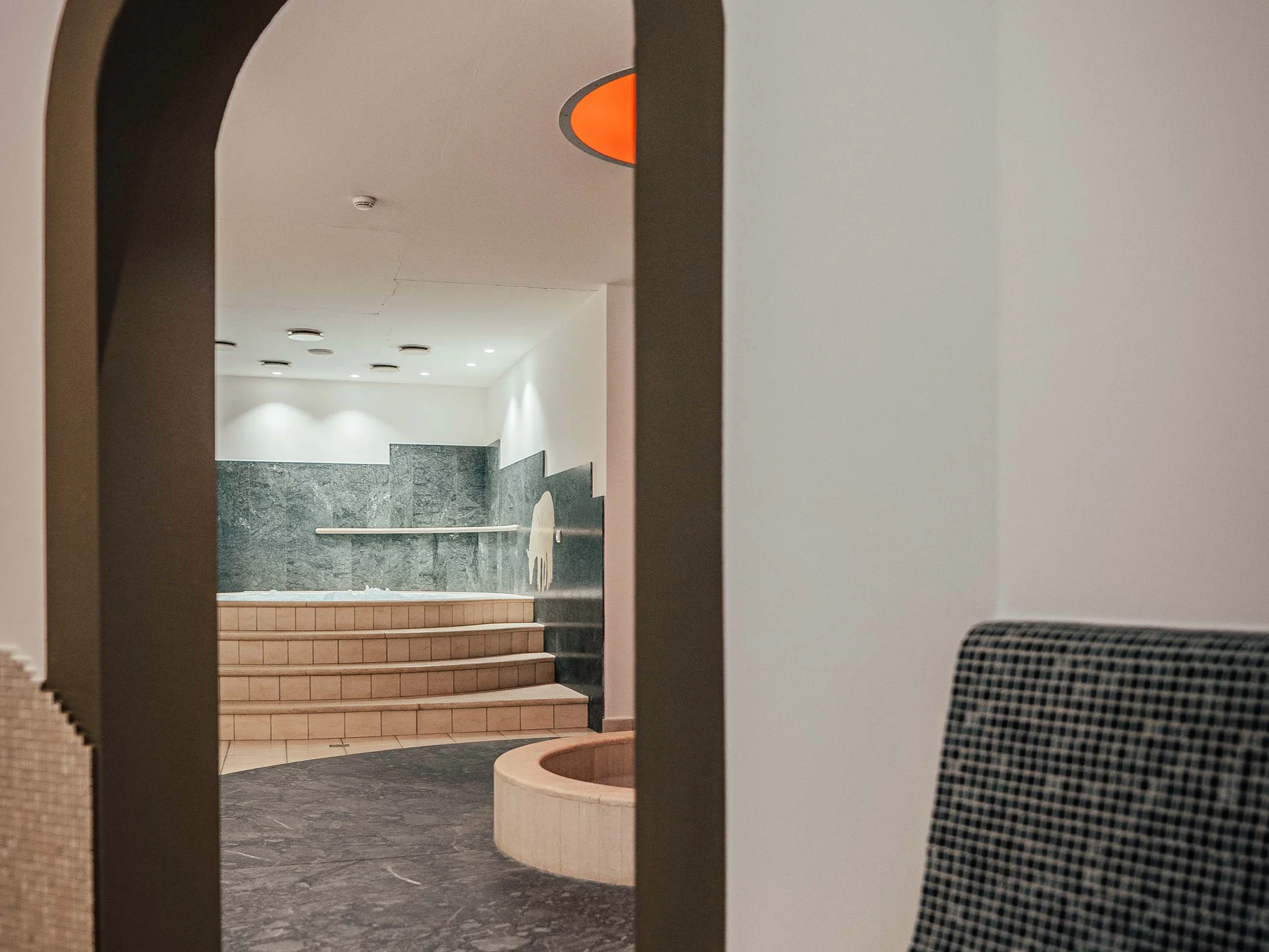 Il vostro hotel con spa vicino a Brunico Vista attraverso un arco su un'area benessere con scale e panca
