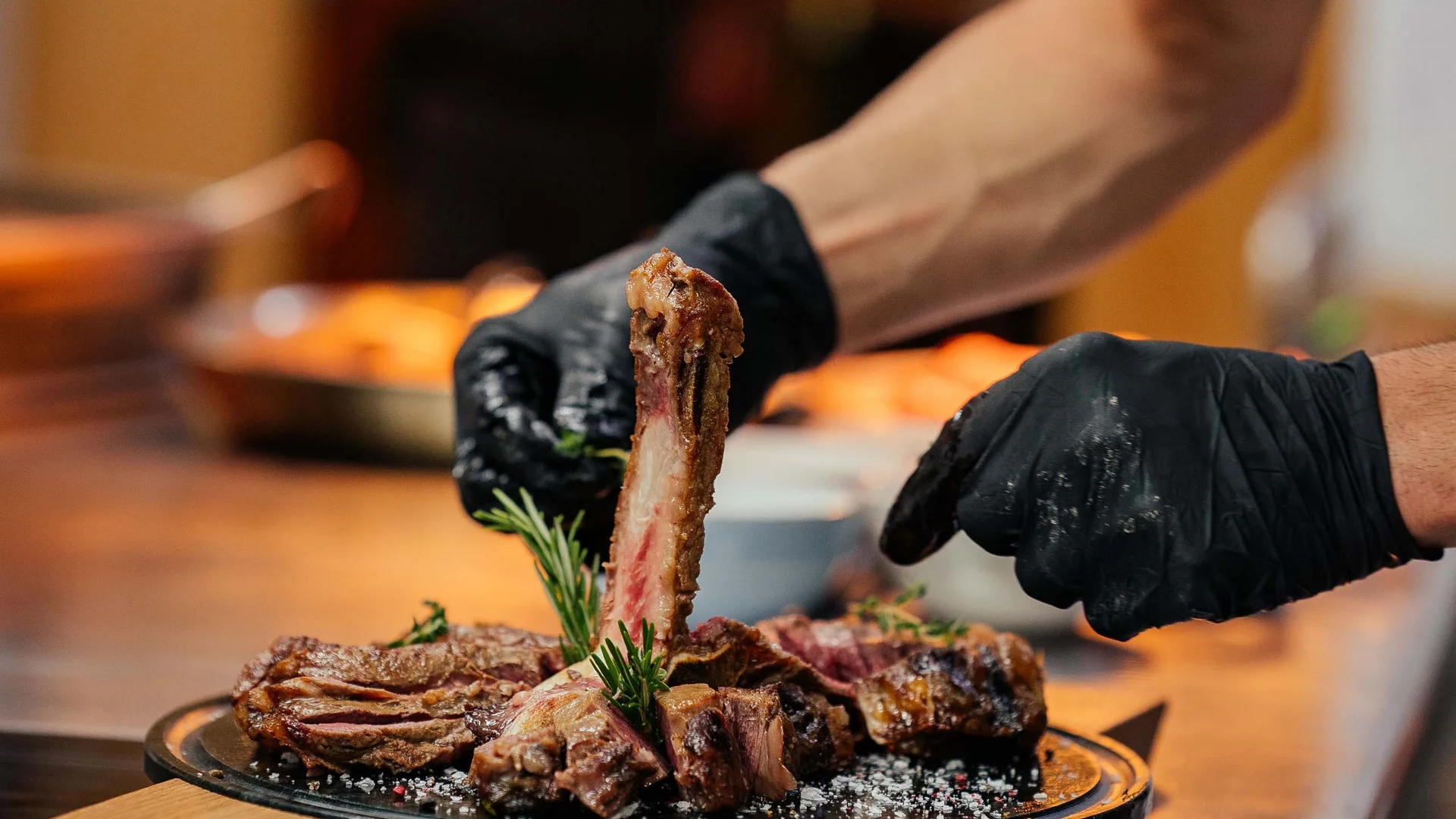 Cuoco sistema costolette di carne grigliata con rosmarino su un piatto