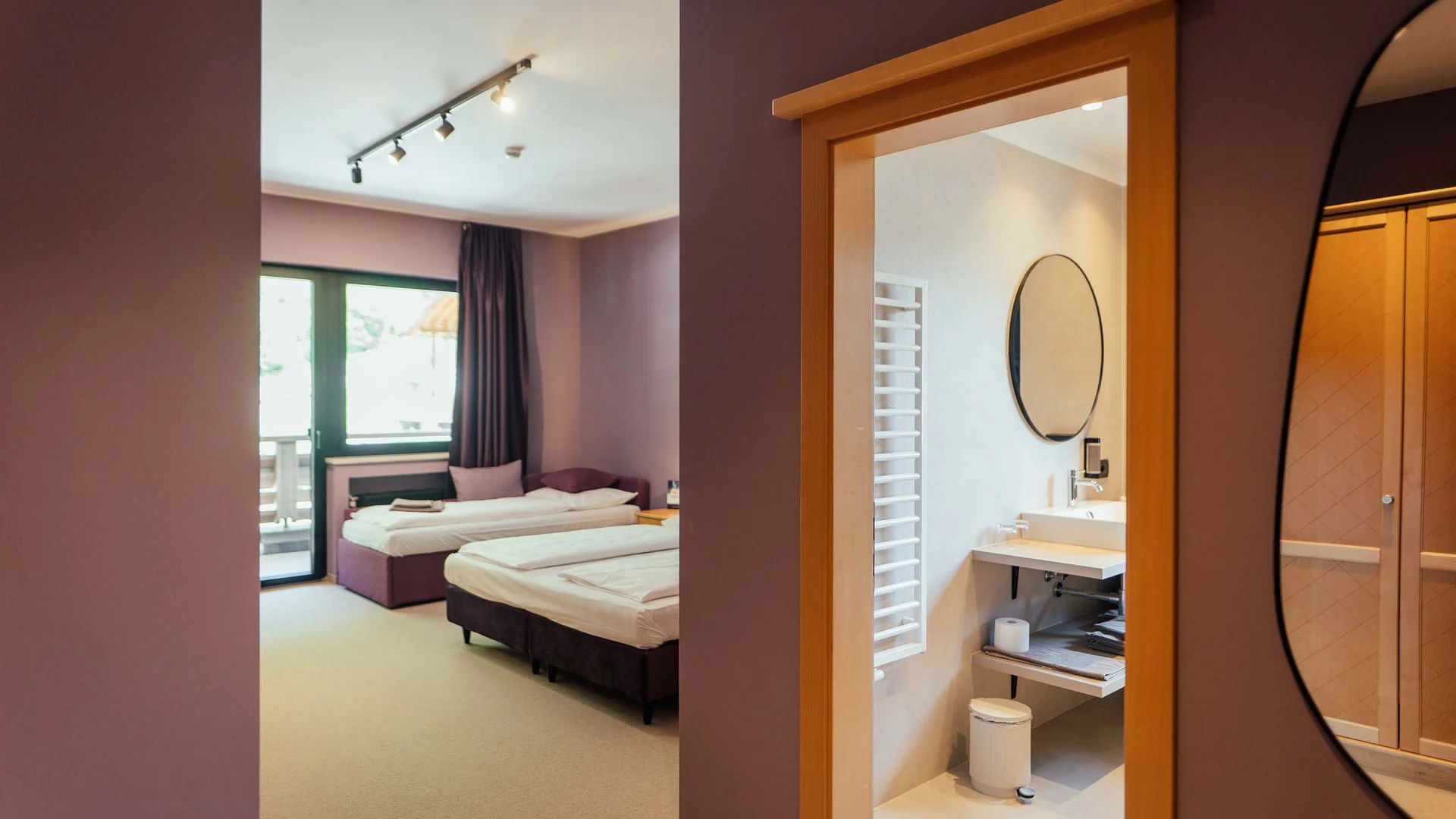 Hotelzimmer mit zwei Einzelbetten, Balkon und angrenzendem Badezimmer mit rundem Spiegel