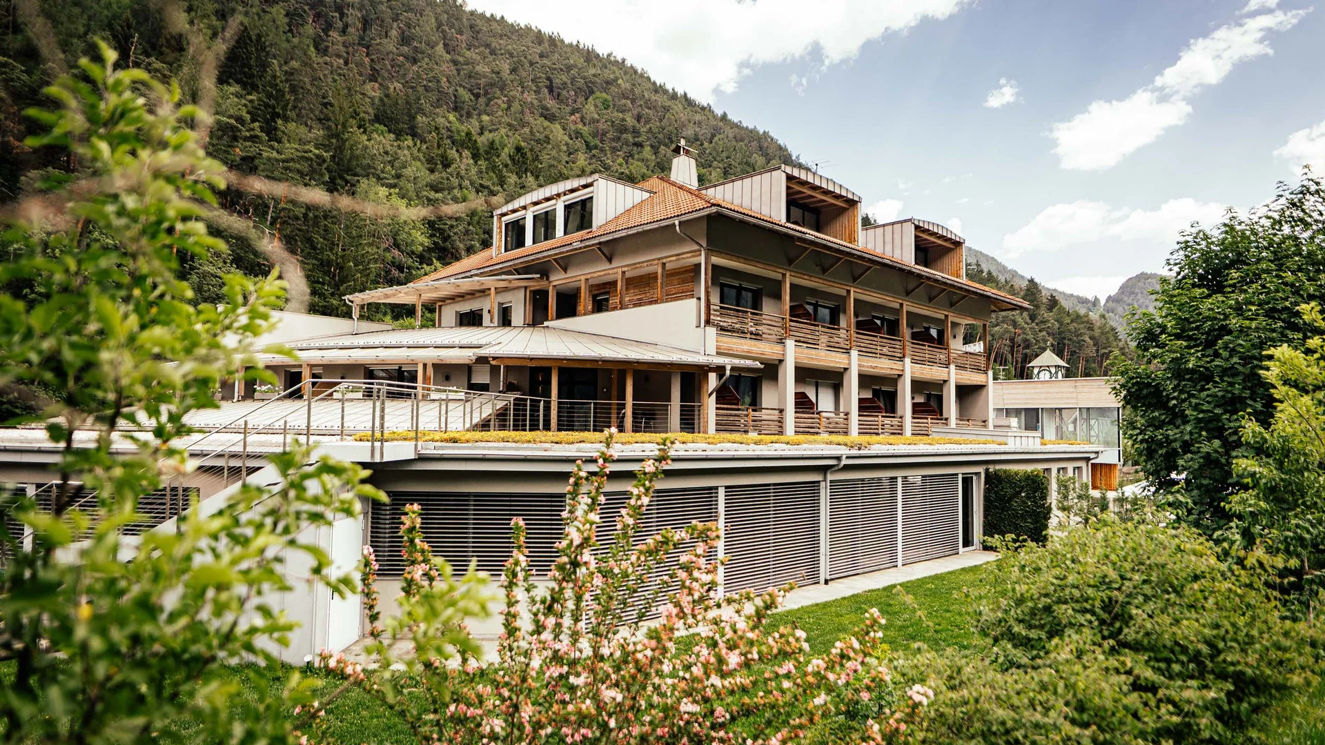 Modernes Hotelgebäude mit Balkonen in grüner Berglandschaft