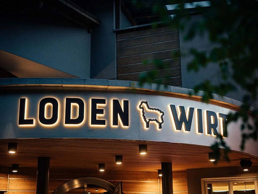 Il Lodenwirt a Vandoies | Hotel, residence e ristorante Insegna illuminata con scritta Loden Wirt e simbolo di lama