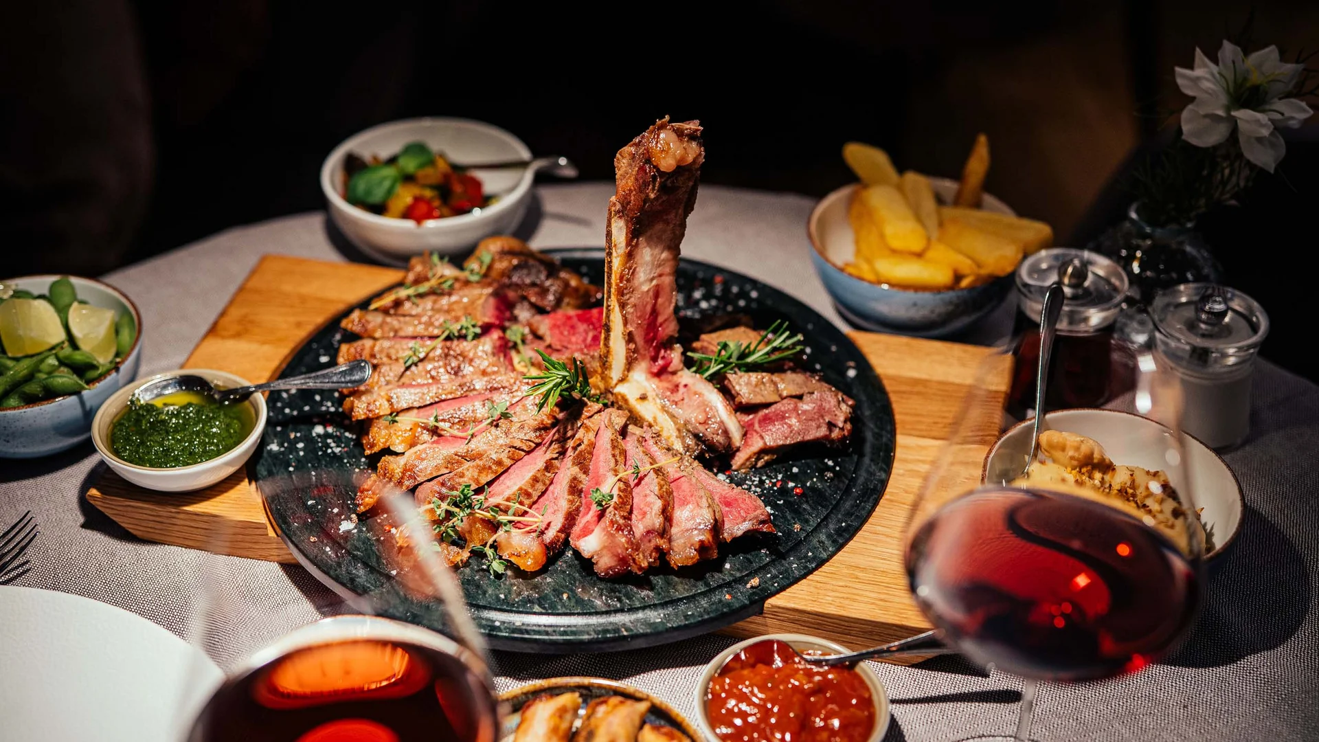 Bistecca alla griglia con contorni e vino rosso su tavola apparecchiata
