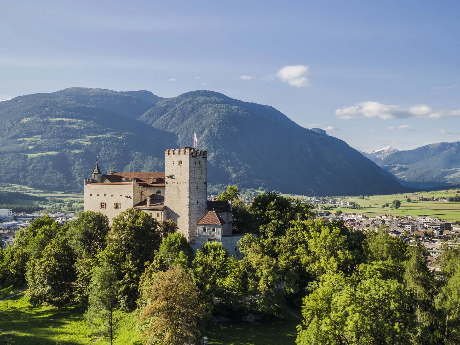Le vostre vacanze in Val Pusteria Castello con torre davanti a montagne, valle e città