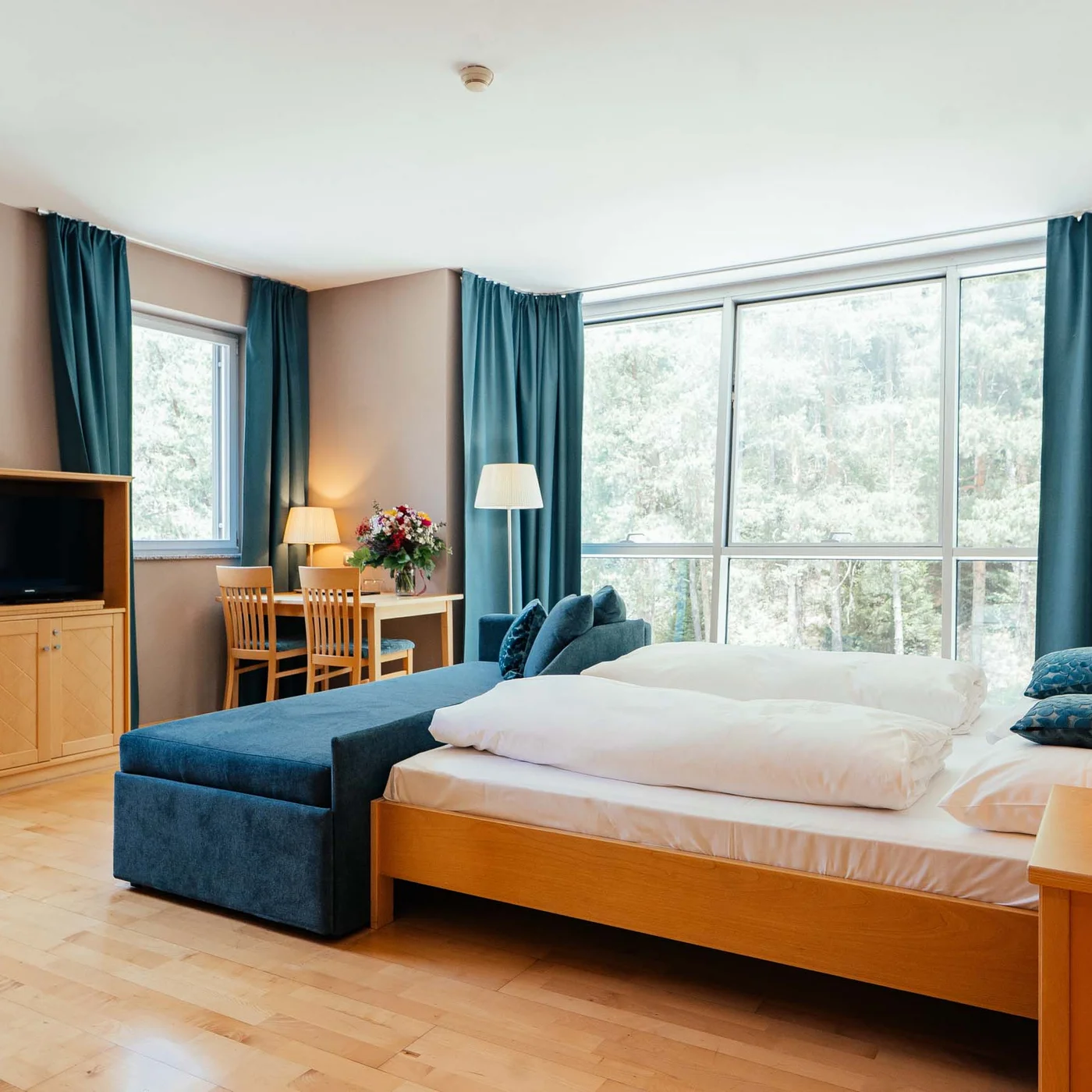 Residence Lodenwirt | Vacanza a Vandoies Camera d'hotel luminosa con letto matrimoniale, tende blu e mobili in legno