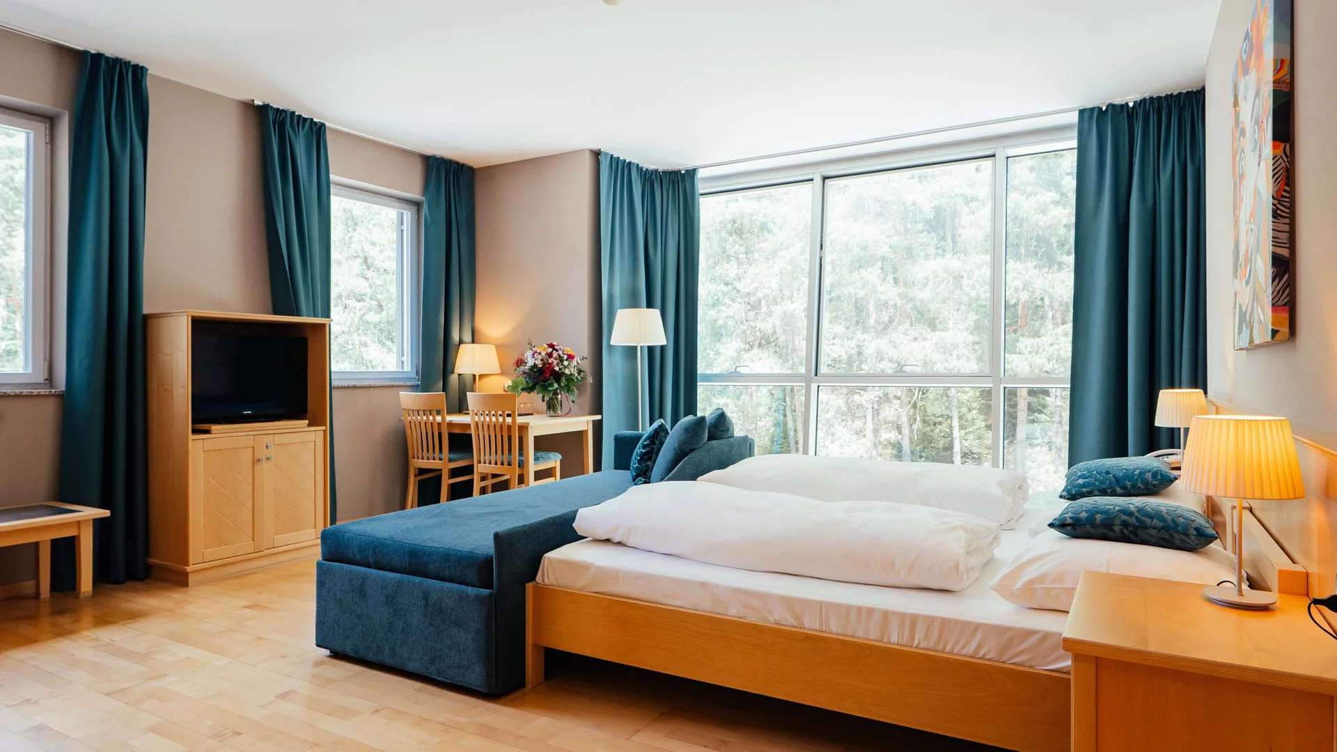 Camera d'hotel luminosa con letto matrimoniale, tende blu e mobili in legno