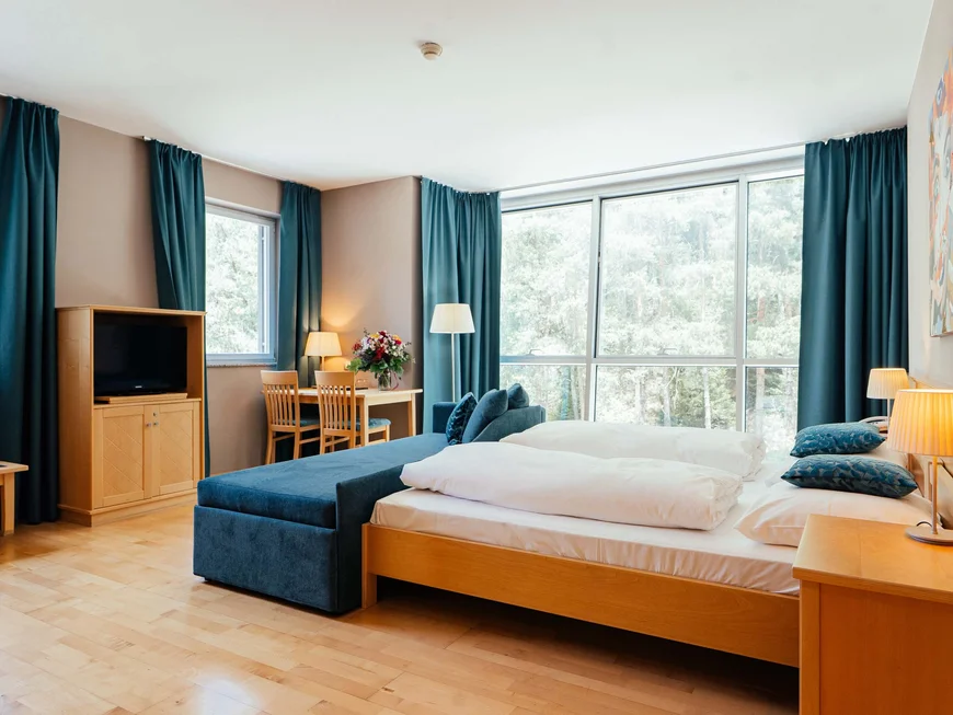 Residence Lodenwirt | Vacanza a Vandoies Camera d'hotel luminosa con letto matrimoniale, tende blu e mobili in legno