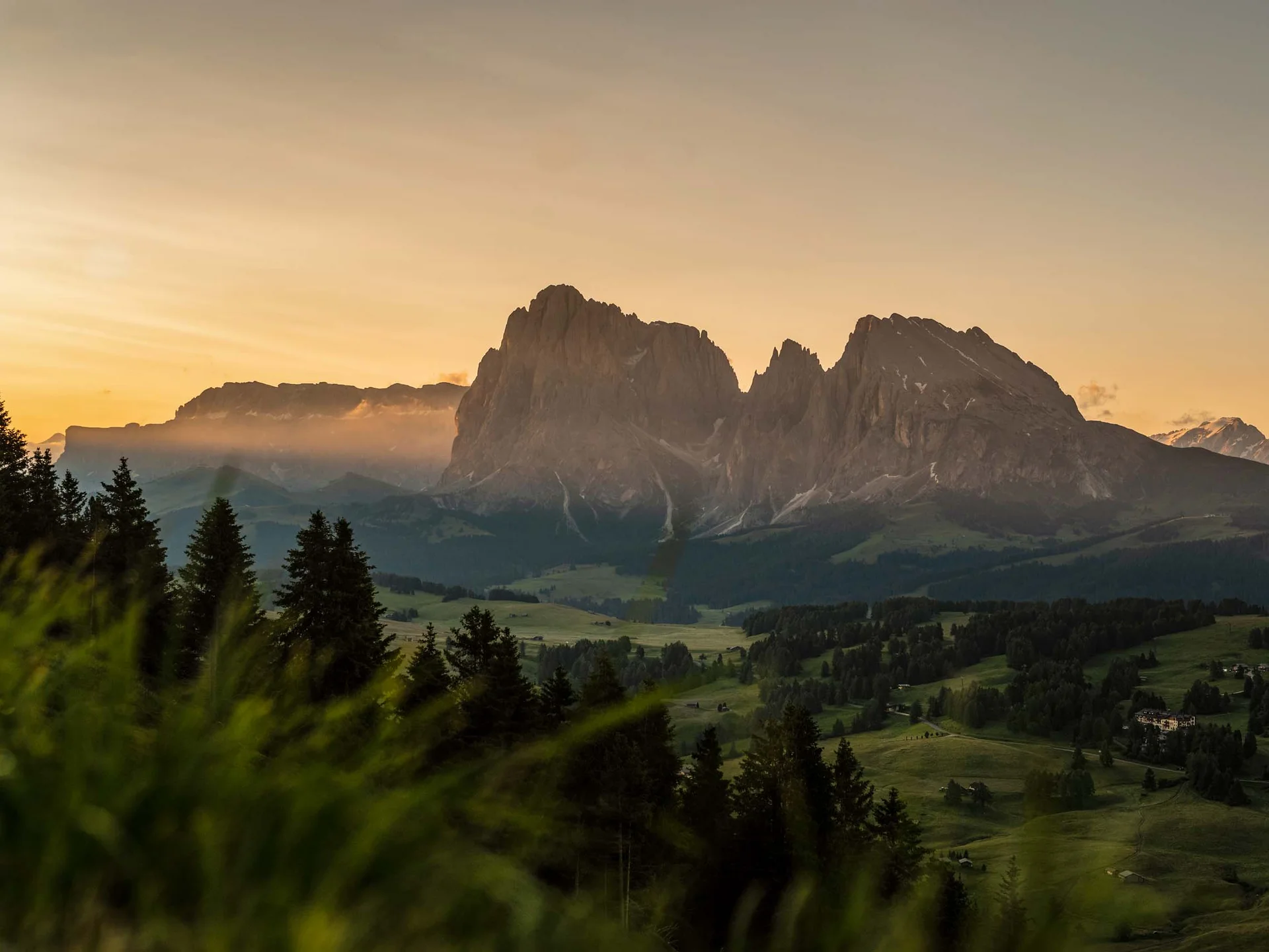 Le vostre vacanze in Val Pusteria Paesaggio montano al tramonto con pendii boscosi e prati verdi