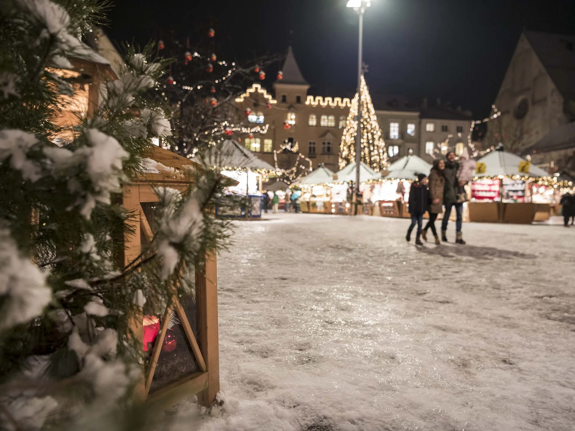 Il Lodenwirt a Vandoies | Hotel, residence e ristorante Mercatino di Natale innevato di notte, con bancarelle illuminate e un albero decorato