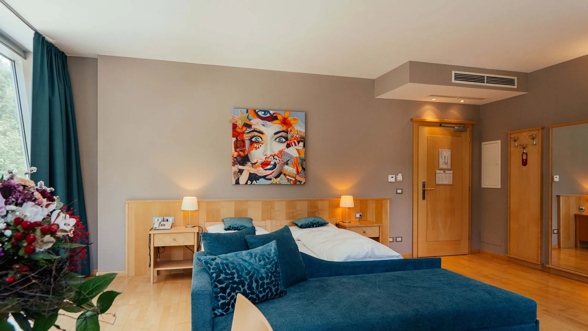 Camera d'hotel moderna con divano blu, letto matrimoniale e arte murale colorata