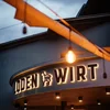 Hotel & Residence Lodenwirt Bildergalerie Beleuchtetes Schild „Joden Wirt“ an einem Gebäude in der Abenddämmerung