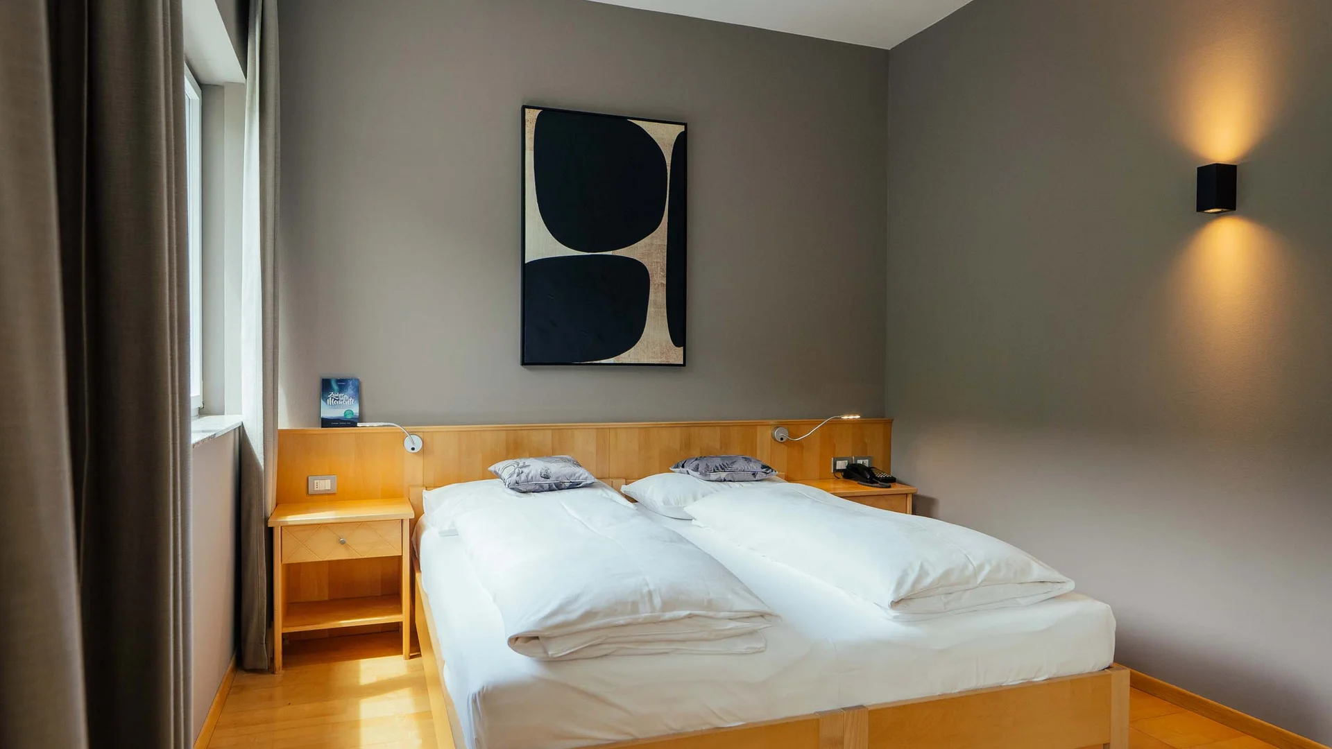 Camera d'hotel moderna con due letti singoli e arte astratta sulla parete