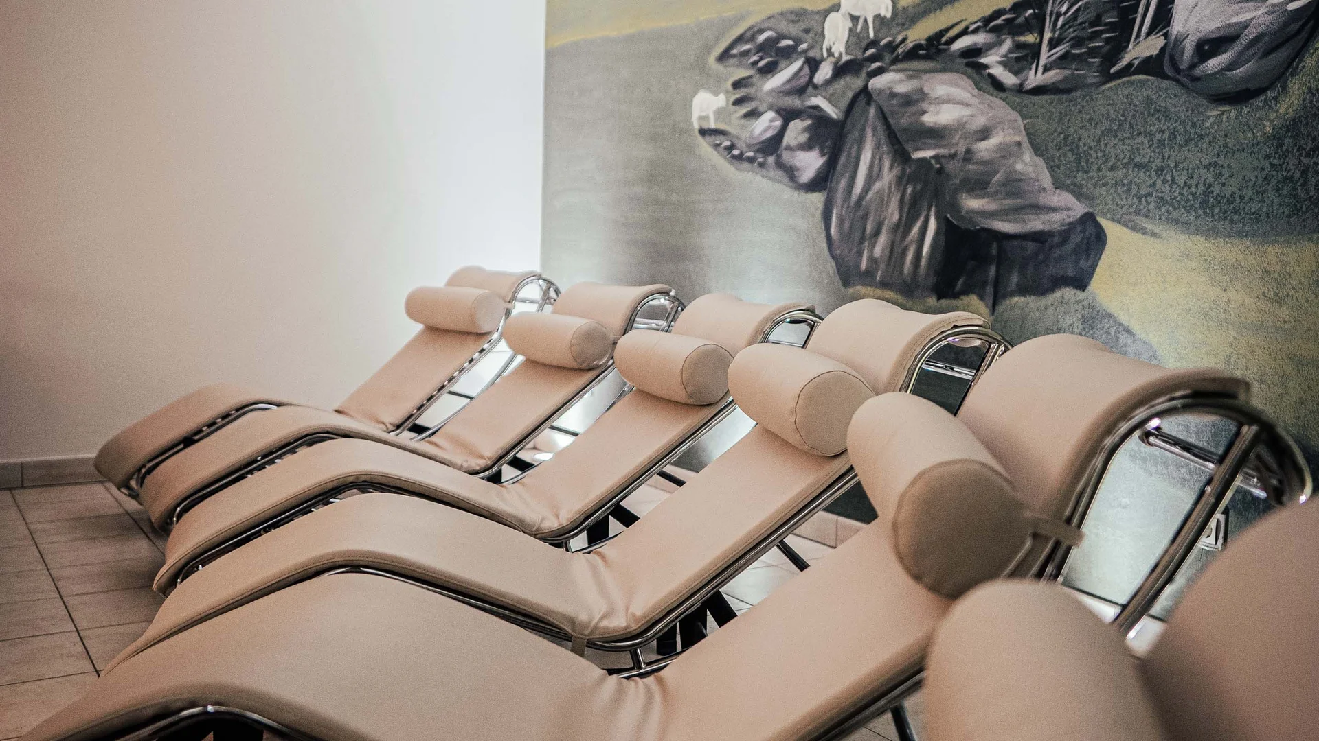 Il vostro hotel con spa vicino a Brunico Fila di comode chaise longue in una stanza benessere tranquilla con murale