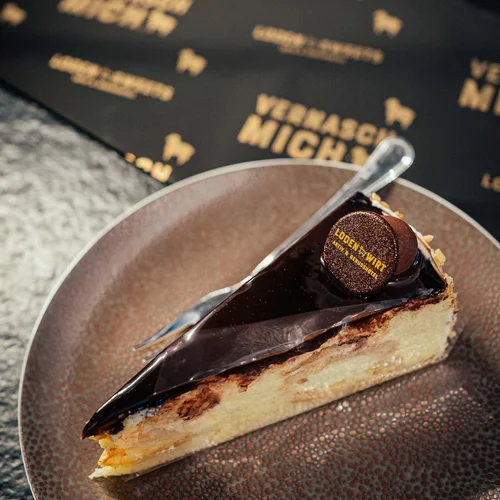Stück Kuchen mit Schokoladenglasur und Dekoration auf braunem Teller