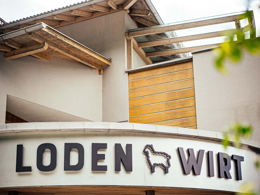 Der Lodenwirt in Vintl | Hotel, Residence & Restaurant Eingang eines Gebäudes mit Schriftzug Loden Wirt und Schaf-Logo