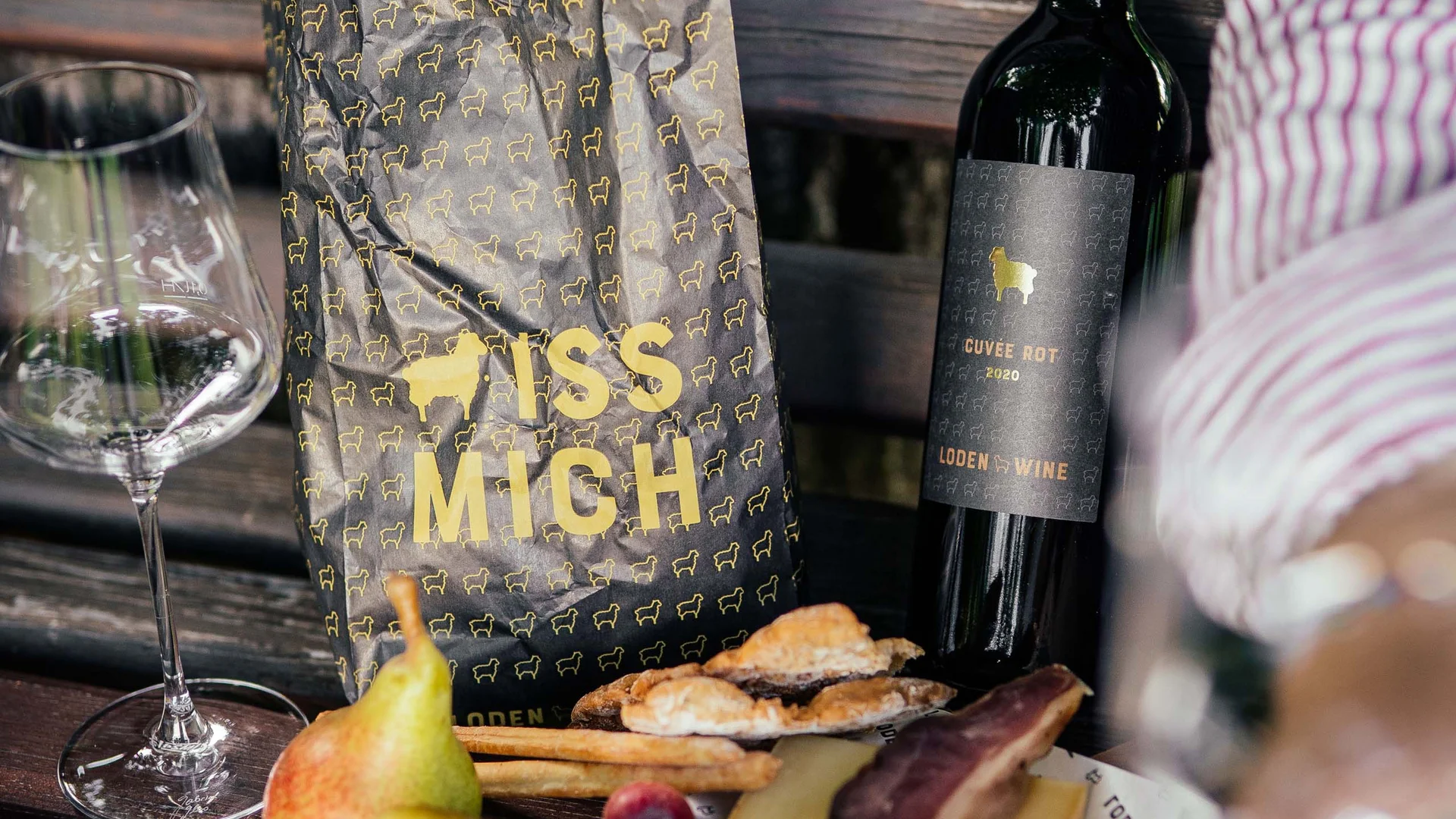 Picnic con vino, formaggio, uva, pera e pane su una panchina di legno
