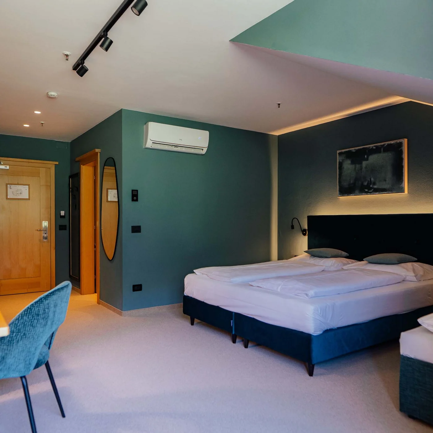 Modern hotel room with double bed, desk, and blue chair