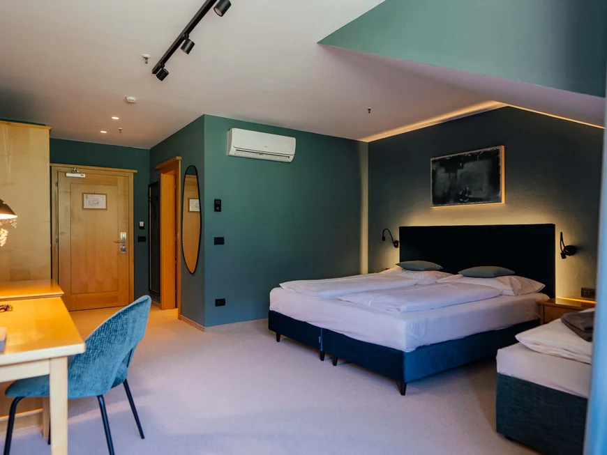 Modern hotel room with double bed, desk, and blue chair