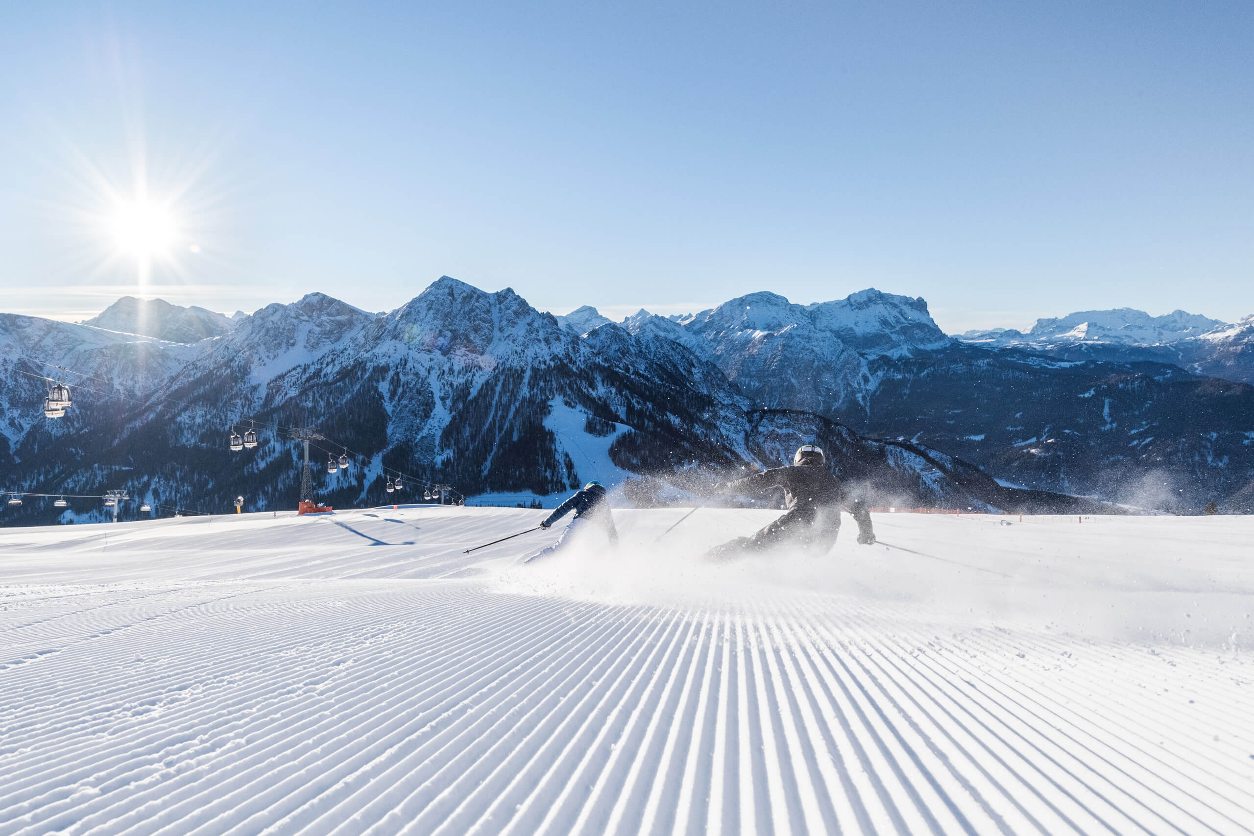 Sciatore su una pista preparata davanti a montagne innevate e seggiovia