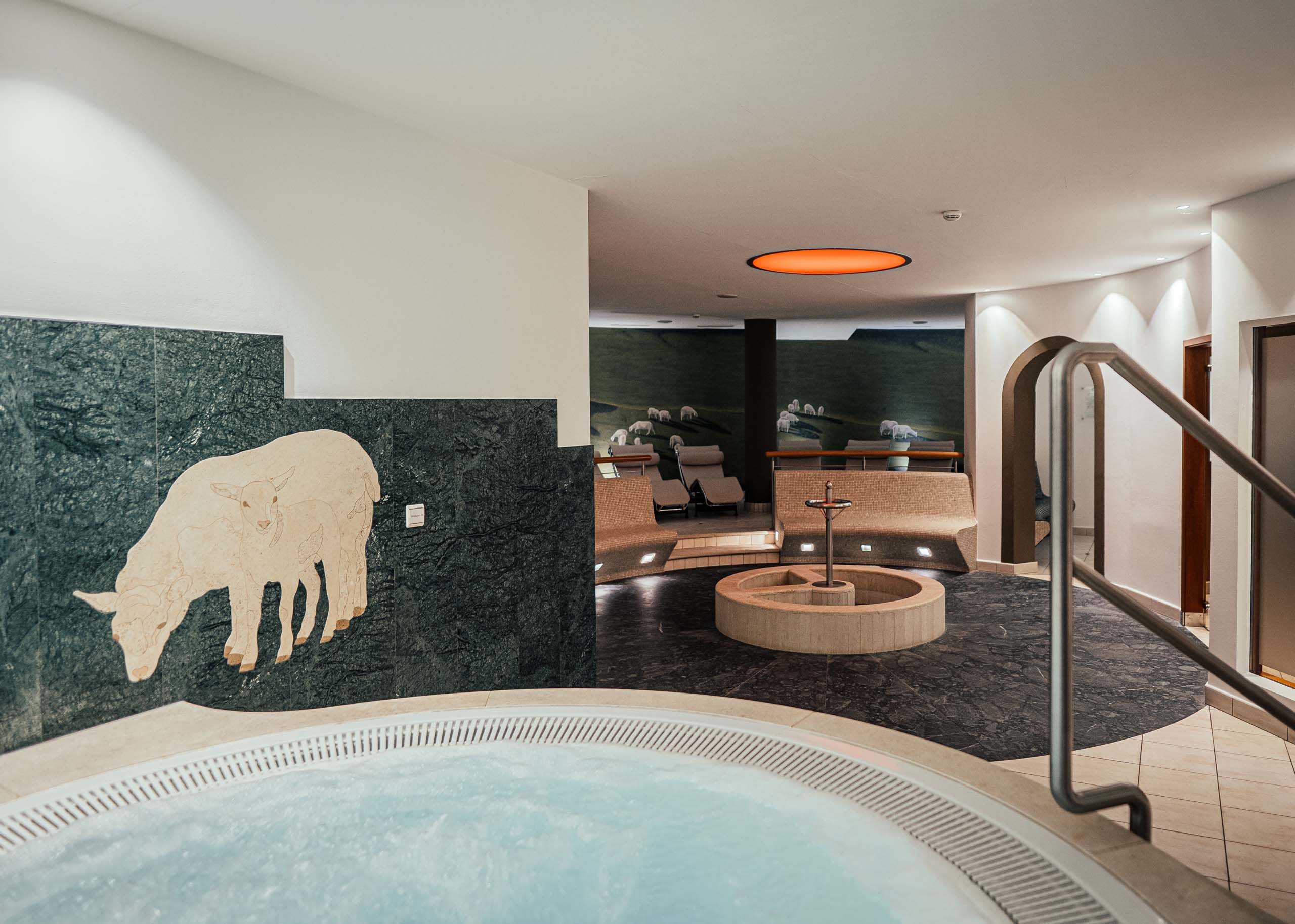 Additionals Innenbereich mit Whirlpool, Sitzbereich und Schafmosaik an der Wand