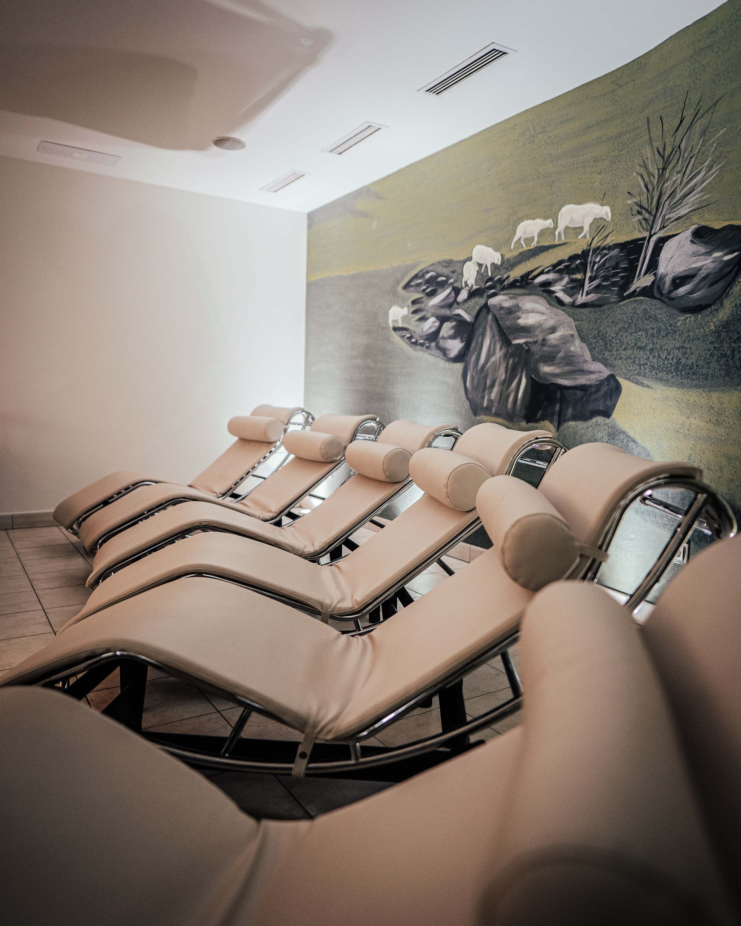 Additionals Fila di comode chaise longue in una stanza benessere tranquilla con murale